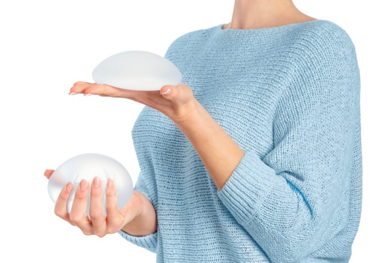 Woman holding and squeezing round implants on white background with clipping path. Mammoplasty and plastic surgery.