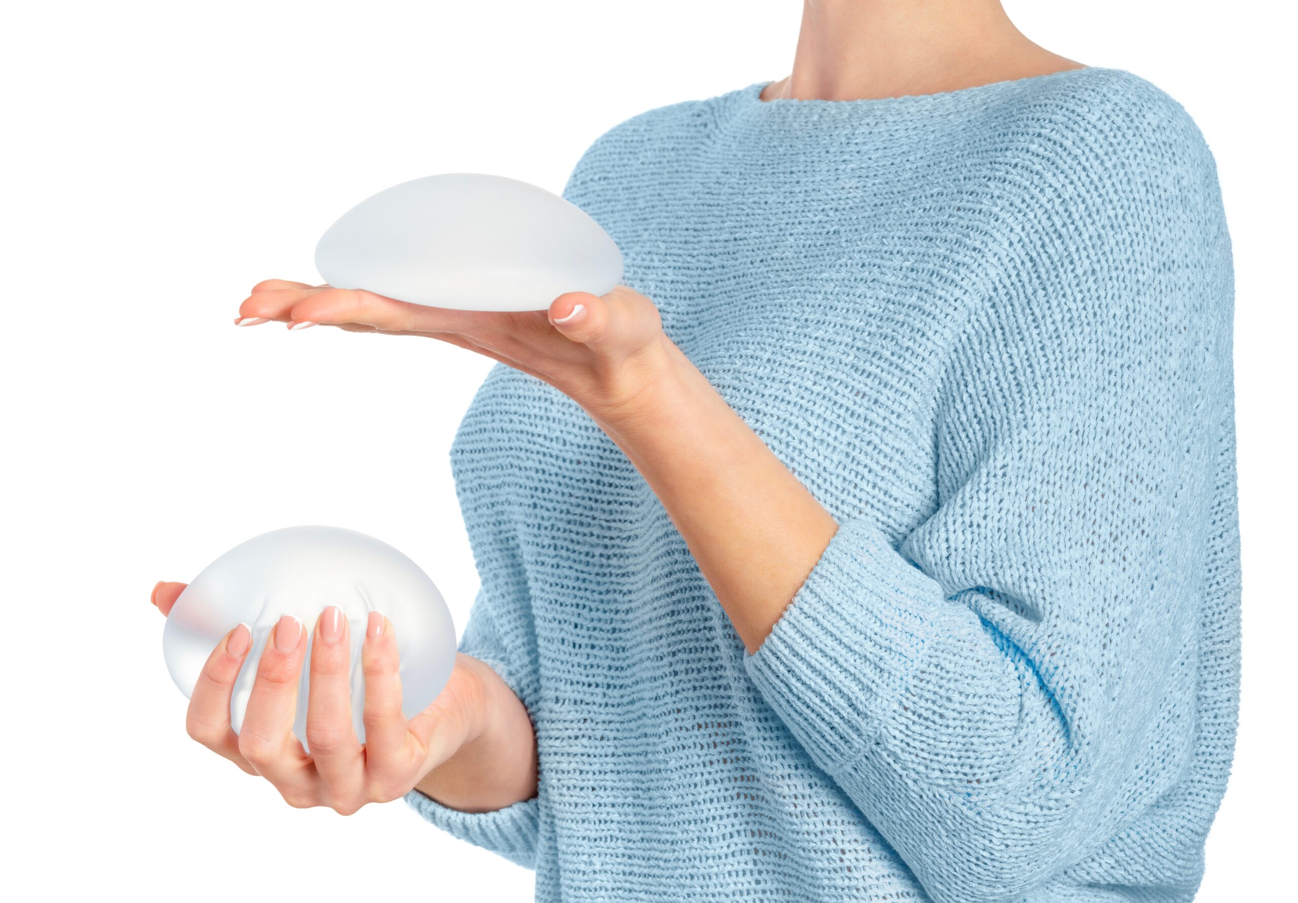 Woman holding and squeezing round implants on white background with clipping path. Mammoplasty and plastic surgery.